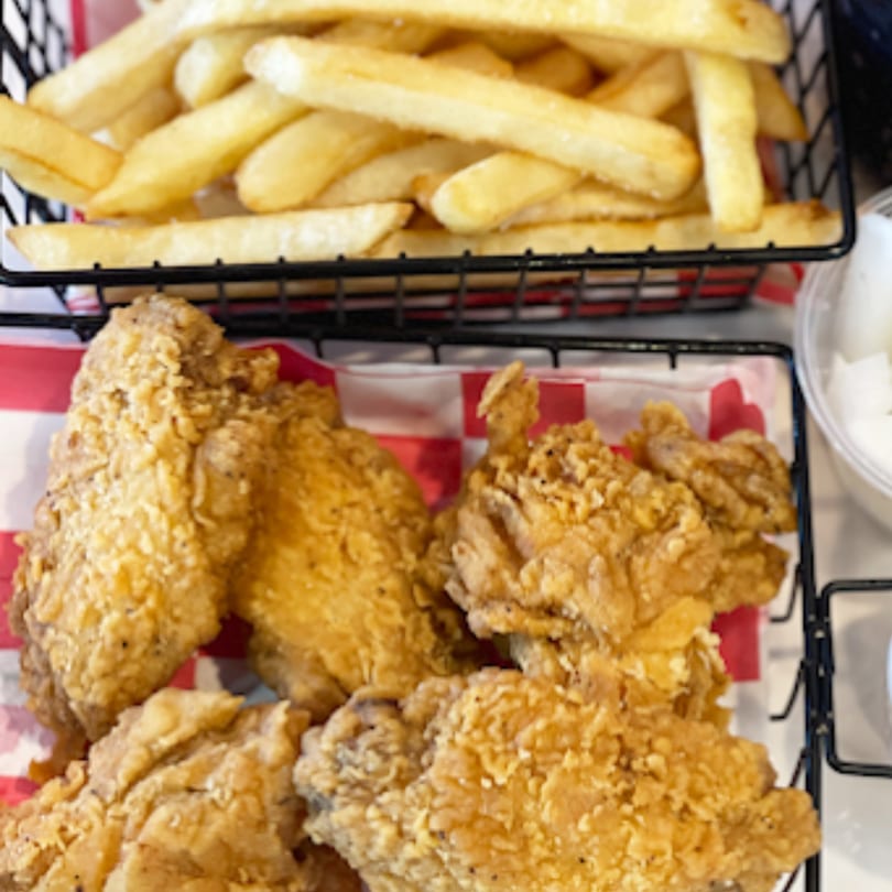 Crispy fried chicken pieces and golden french fries served in black wire baskets.